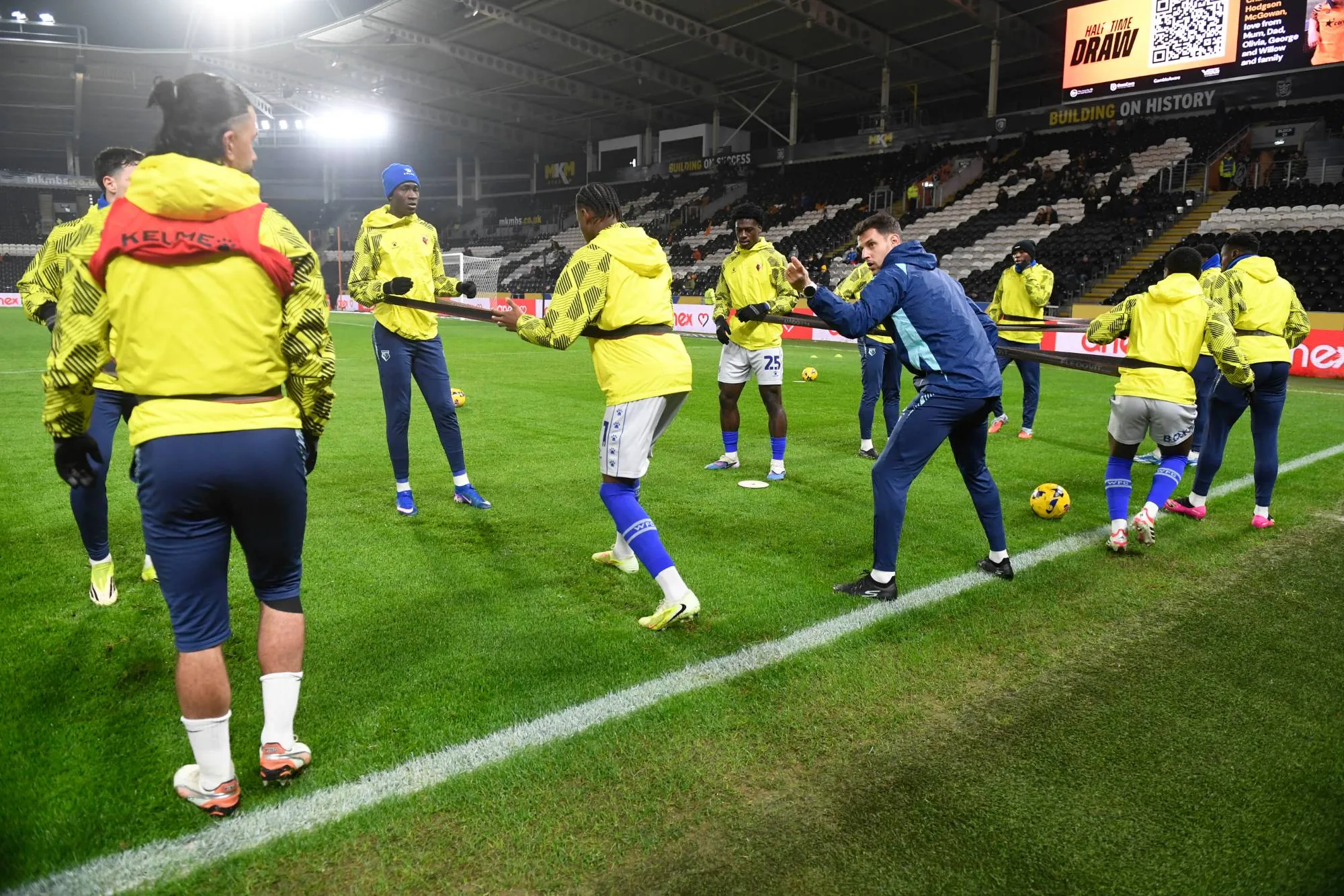 Joel Donés leading a resistance-band warm-up before a Watford FC away match